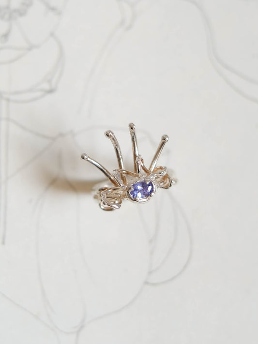 Silver ring with a purple gemstone on a white background